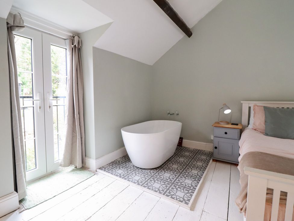 A bedroom with a bathtub and a bed at Riverwash Cottage in Dwygyfylchi