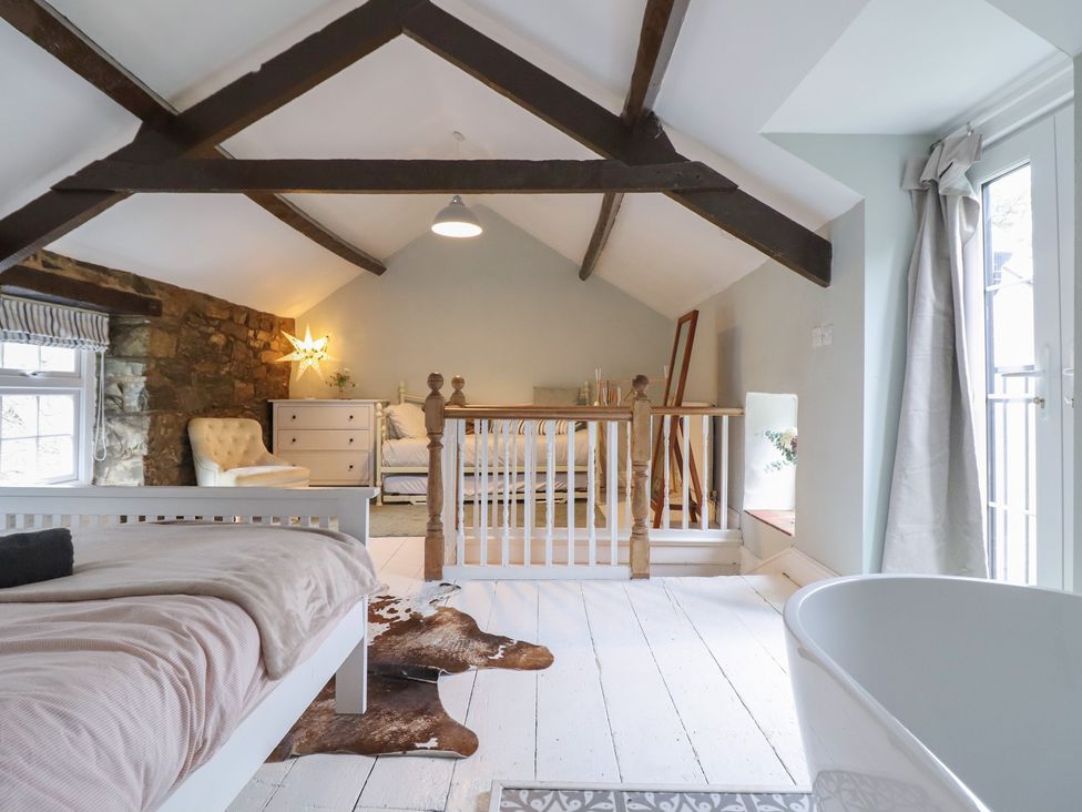 A bedroom with a bed and a bathtub at Riverwash Cottage Dwygyfylchi