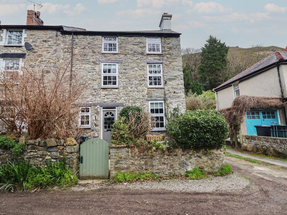 A stone cottage with a door and windows at Riverwash Cottage Dwygyfylchi
