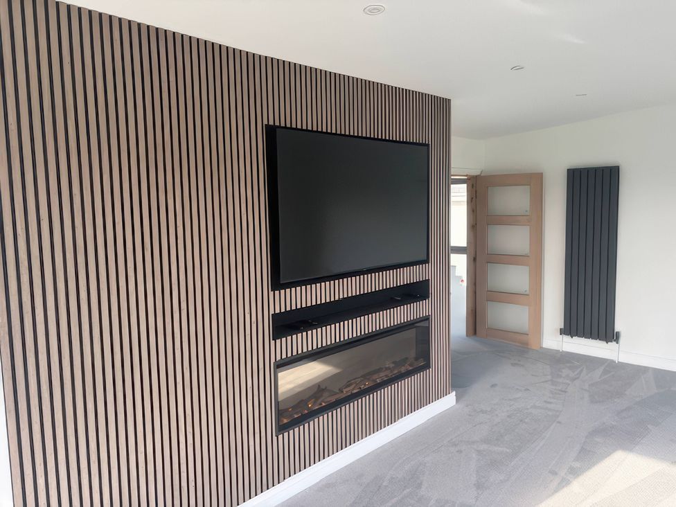 A living room with a television and fireplace at Seaddler in Trearddur Bay