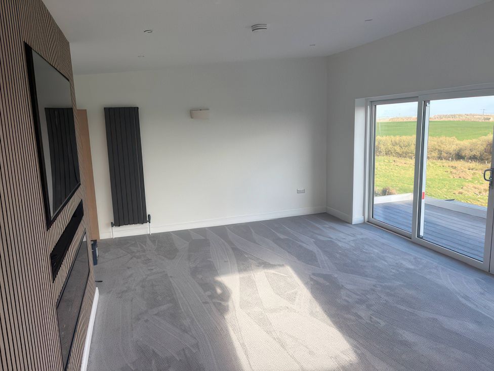 A living room with a television and a radiator at Seaddler in Trearddur Bay