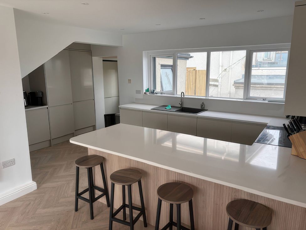 A kitchen with a sink and bar stools at Seaddler in Trearddur Bay