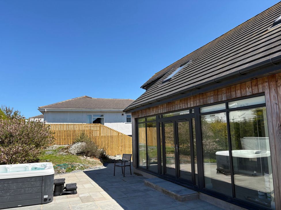 An outdoor area with a hot tub and a chair at Seaddler in Trearddur Bay