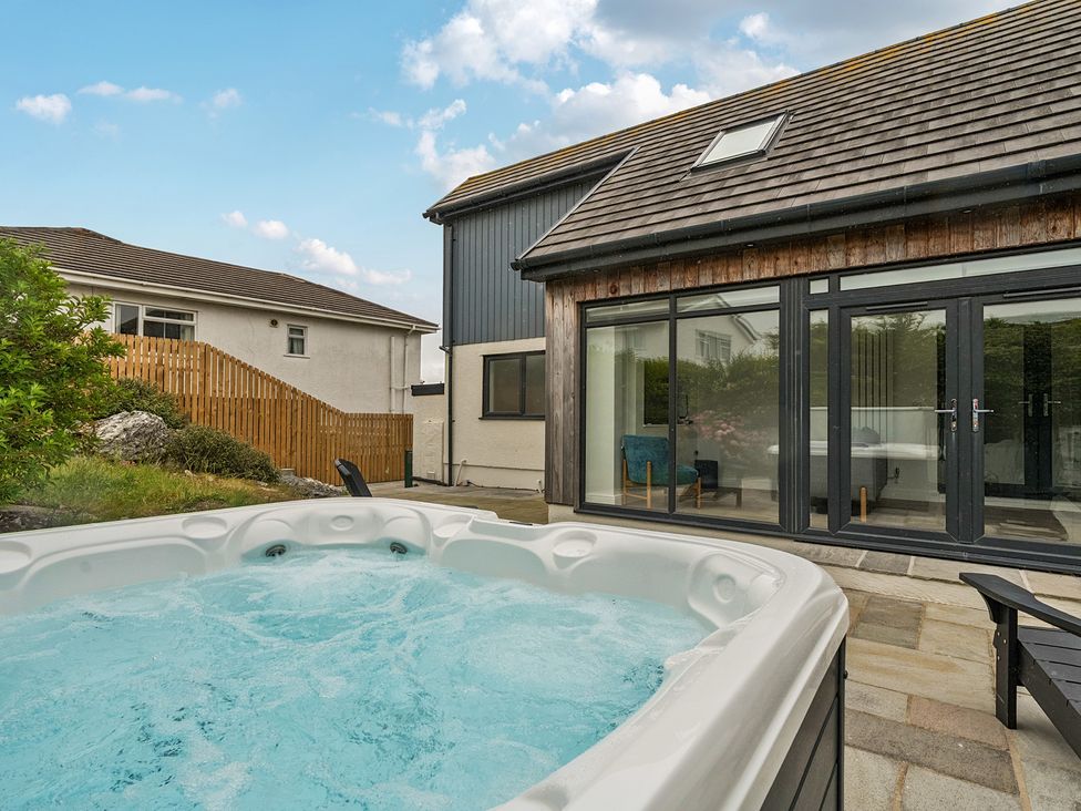 An outdoor area with a hot tub and stone patio at Seaddler in Trearddur Bay