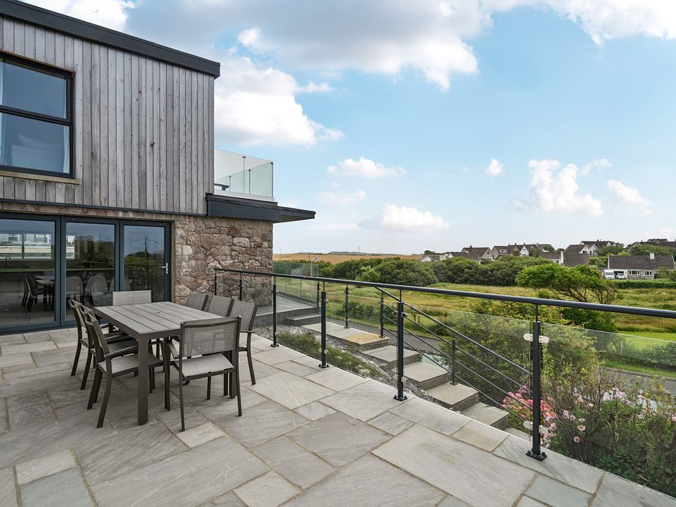 An outdoor patio area with a table and chairs at Seaddler in Trearddur Bay