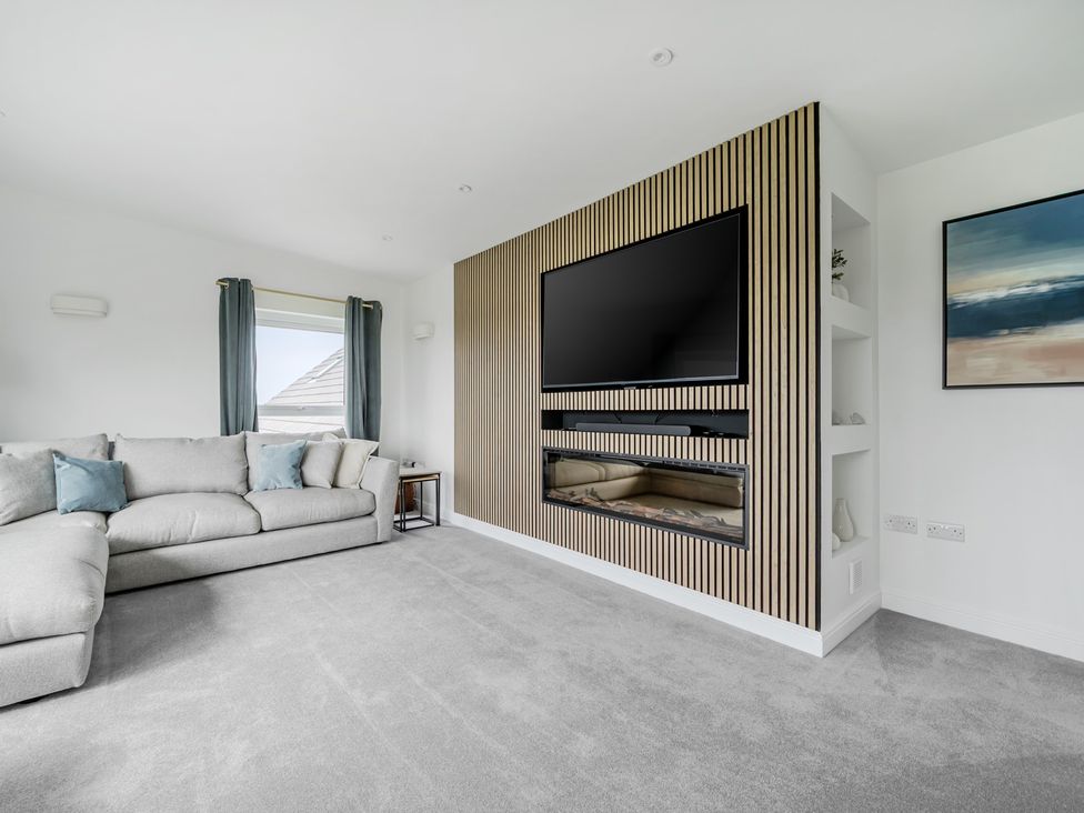 A living room with a sofa and television at Seaddler in Trearddur Bay