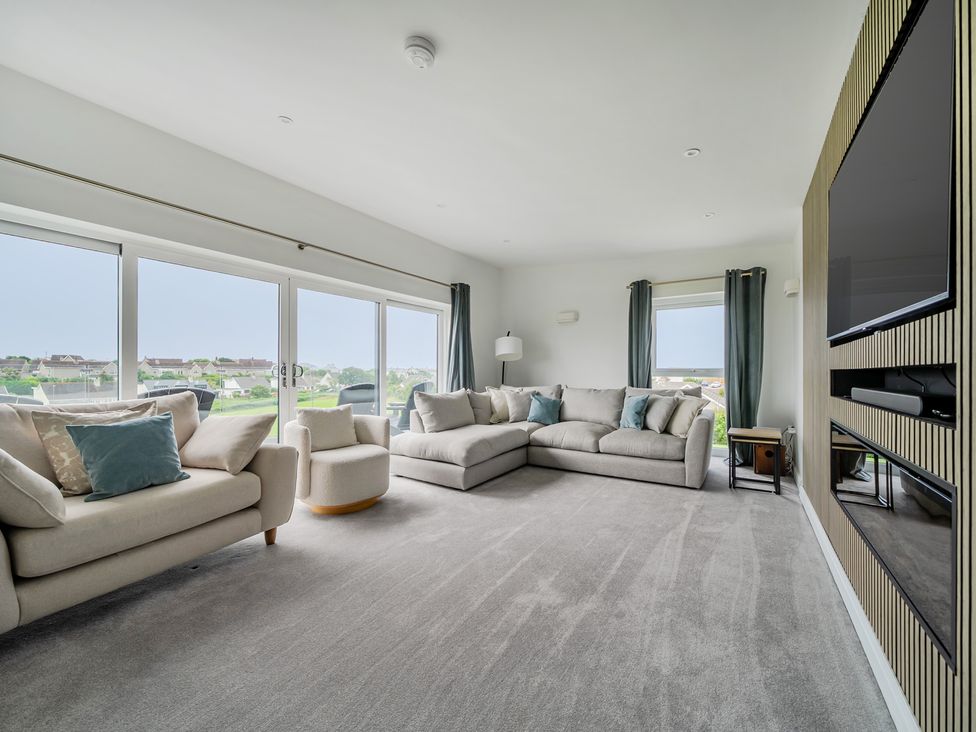 A living room with sofa and television at Seaddler in Trearddur Bay