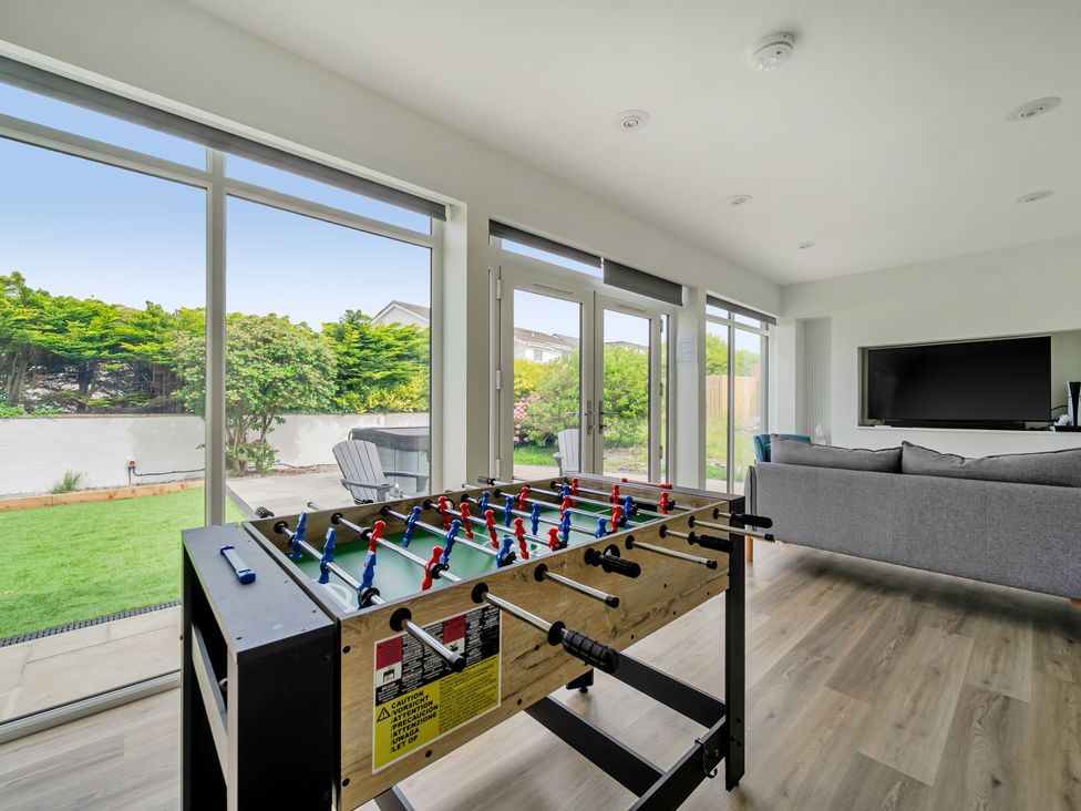 A living room with a foosball table and television at Seaddler in Trearddur Bay