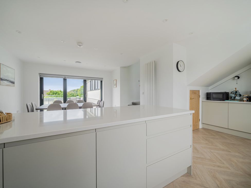 A kitchen with a dining table and chairs at Seaddler in Trearddur Bay
