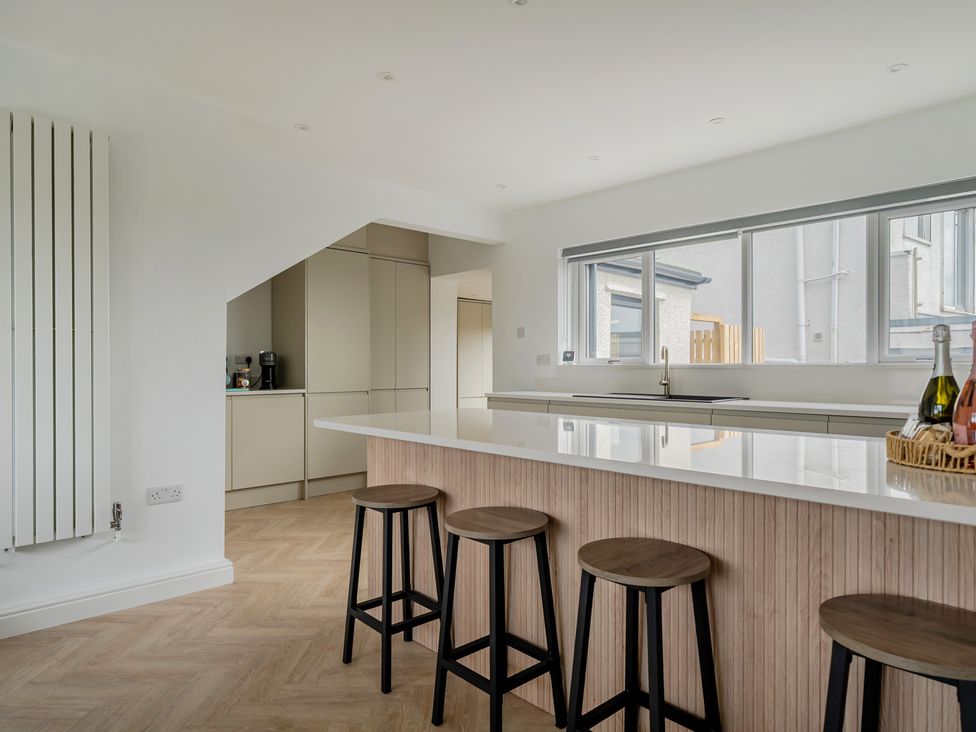 A kitchen with a large island and bar stools at Seaddler Trearddur Bay