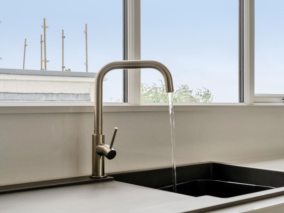 A sink with a faucet running water at Seaddler in Trearddur Bay