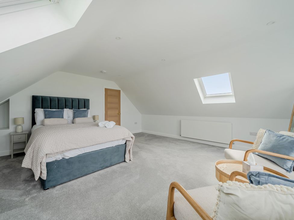 A bedroom with a bed and armchair at Seaddler in Trearddur Bay