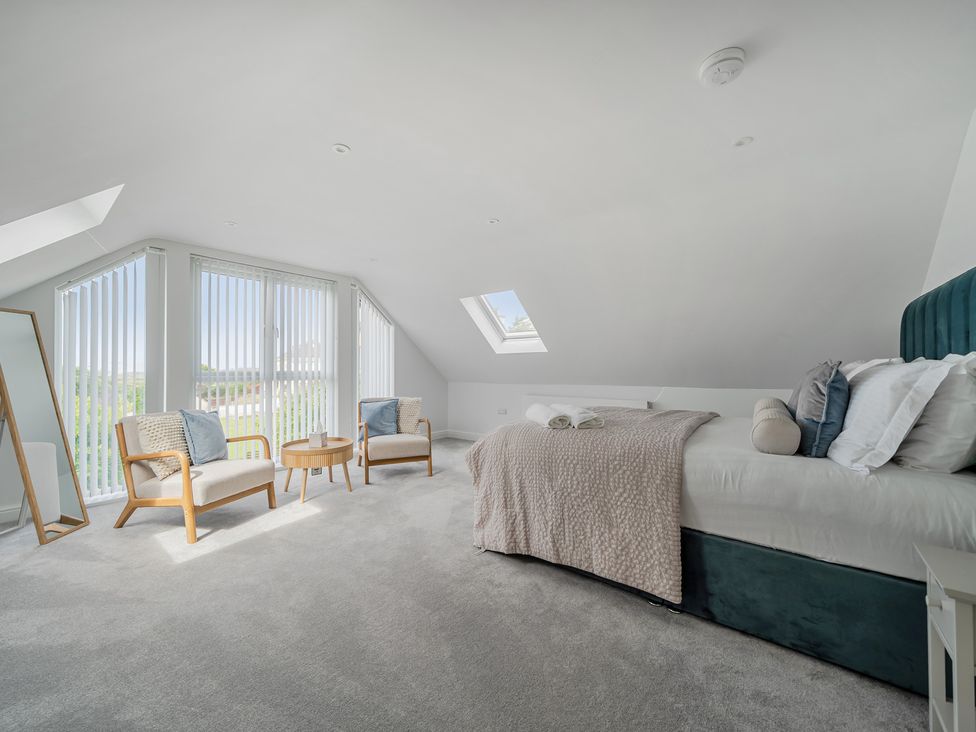 A bedroom with a bed and chairs at Seaddler in Trearddur Bay