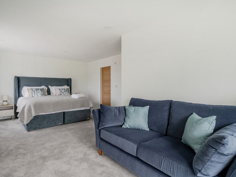 A bedroom with a bed and sofa at Seaddler in Trearddur Bay