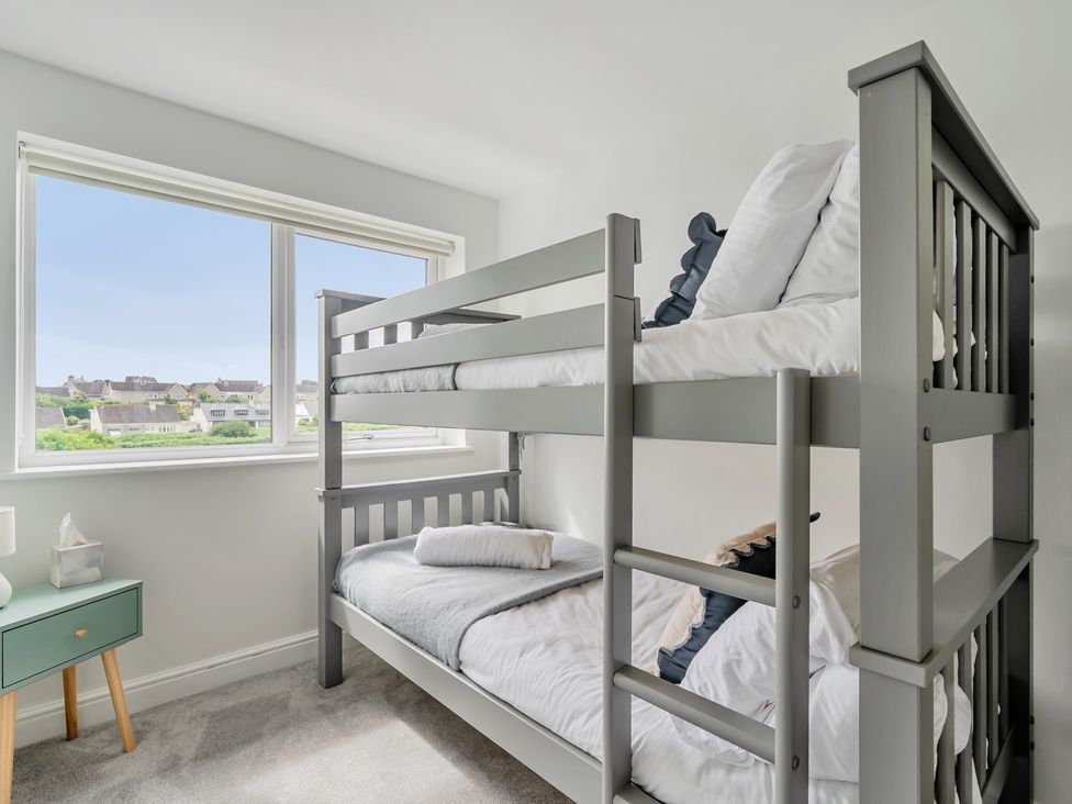 A bedroom with a bunk bed and nightstand at Seaddler in Trearddur Bay