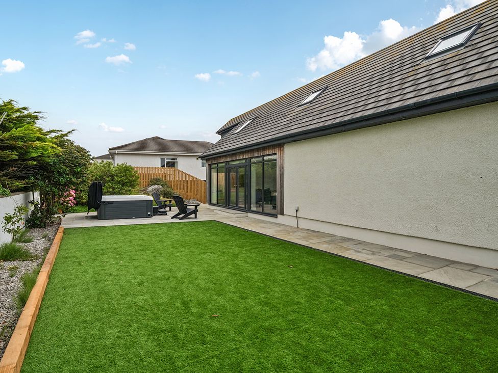 A garden with grass and a hot tub at Seaddler in Trearddur Bay