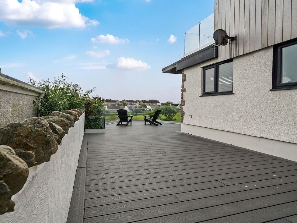 An outdoor deck with chairs and plants at Seaddler in Trearddur Bay