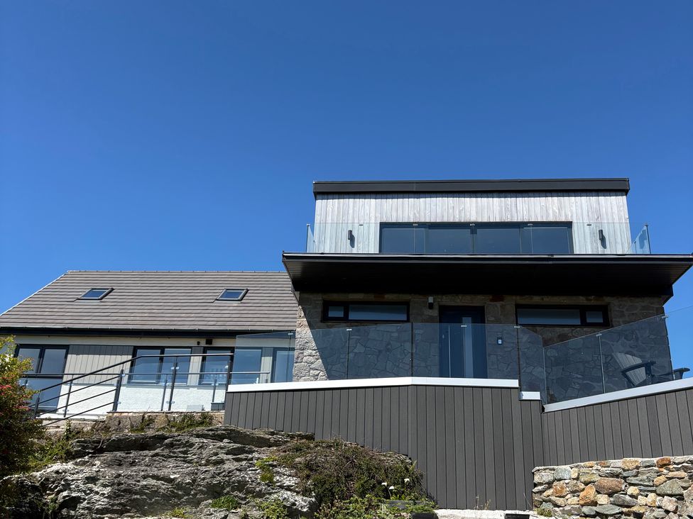 A house with a balcony and stone wall at Seaddler in Trearddur Bay