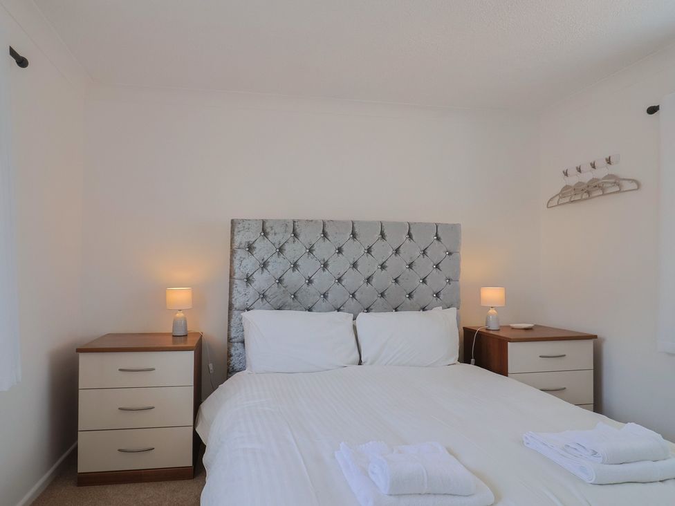 A bedroom with a bed and two bedside tables with lamps and towels on the bed at SubLyme in Lyme Regis