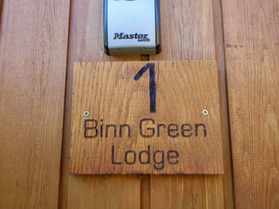 A wooden sign displaying '1 Binn Green Lodge' and a lock on a door