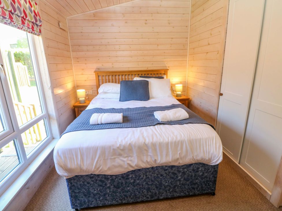 A bedroom with a bed and bedside table at Dovestone Luxury Lodges (sleeps 4) - pets welcome, Greenfield