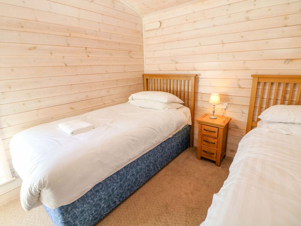 A bedroom with two beds and a nightstand with a lamp at Dovestone Luxury Lodges (sleeps 4) - pets welcome, Greenfield