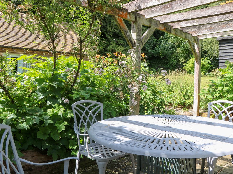 A garden with a table and chairs under a pergola at 3 Malthouse Cottages, Chawton near Alton