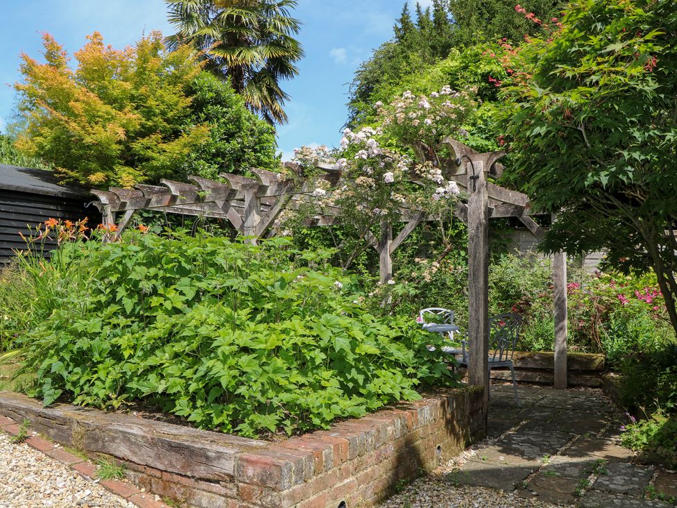A garden with a pergola and flowers at 3 Malthouse Cottages in Chawton near Alton