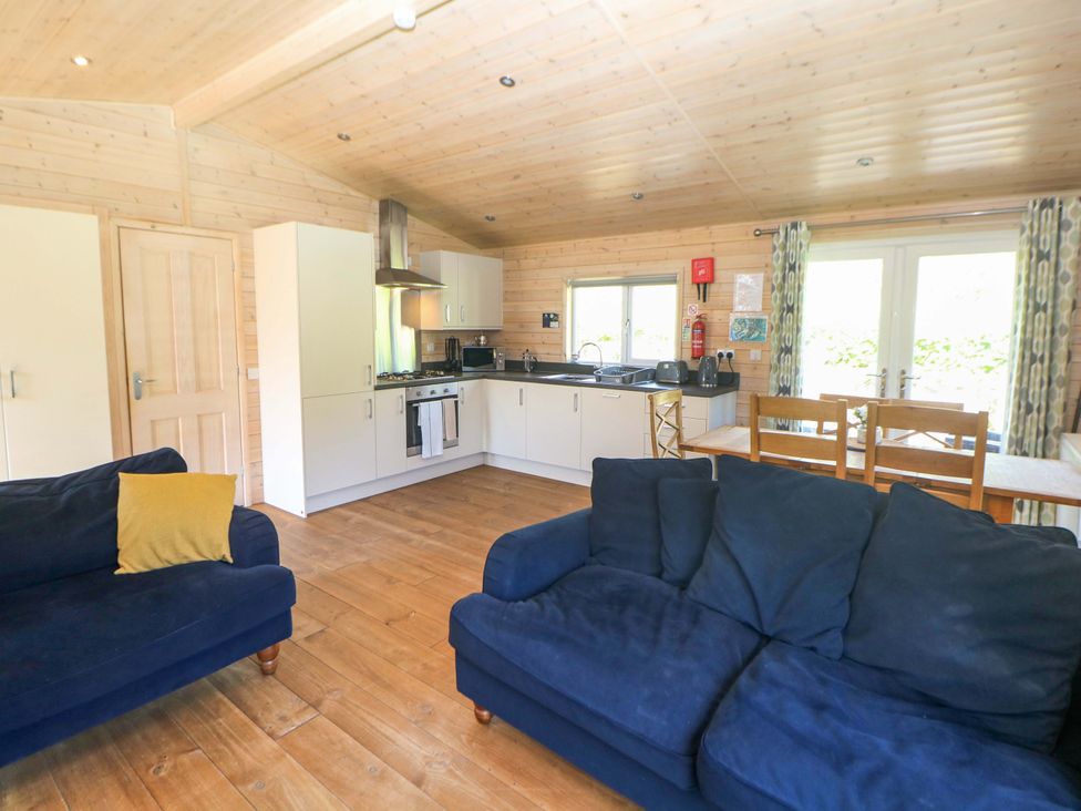 A kitchen with a sofa, kitchen units, and dining table at Dovestone Luxury Lodges (sleeps 6) - pet free Greenfield