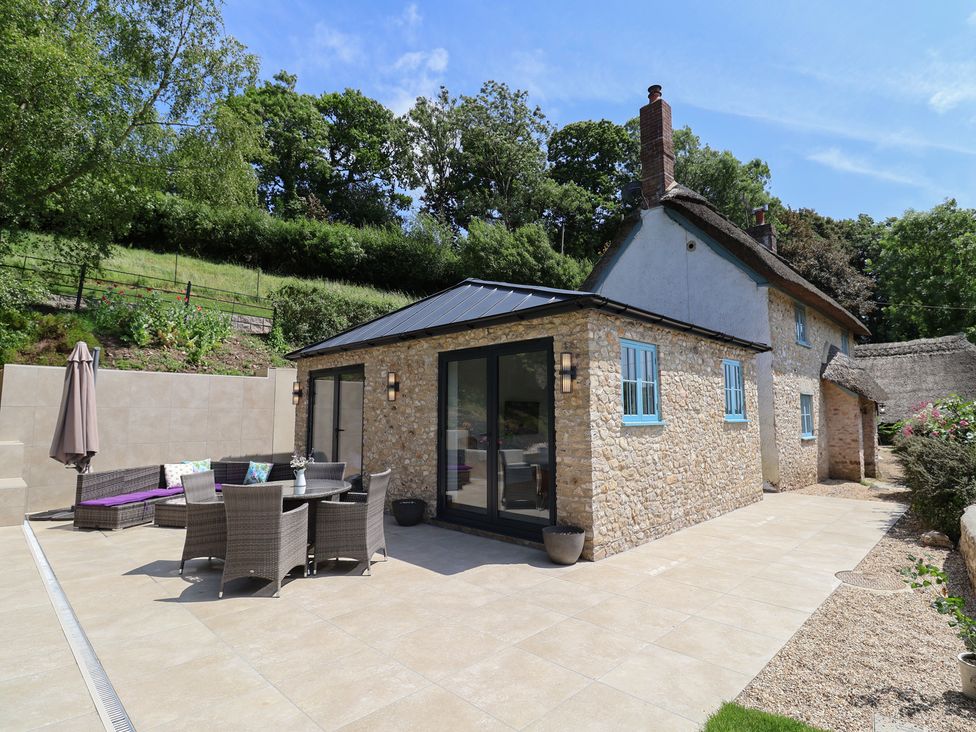 An outdoor seating area with a table and chairs at Upper Cottage Rocombe near Uplyme