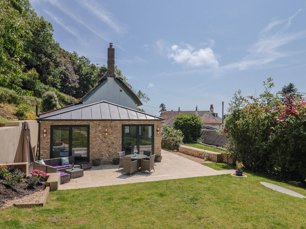 A garden with a patio, table and chairs at Upper Cottage in Rocombe near Uplyme