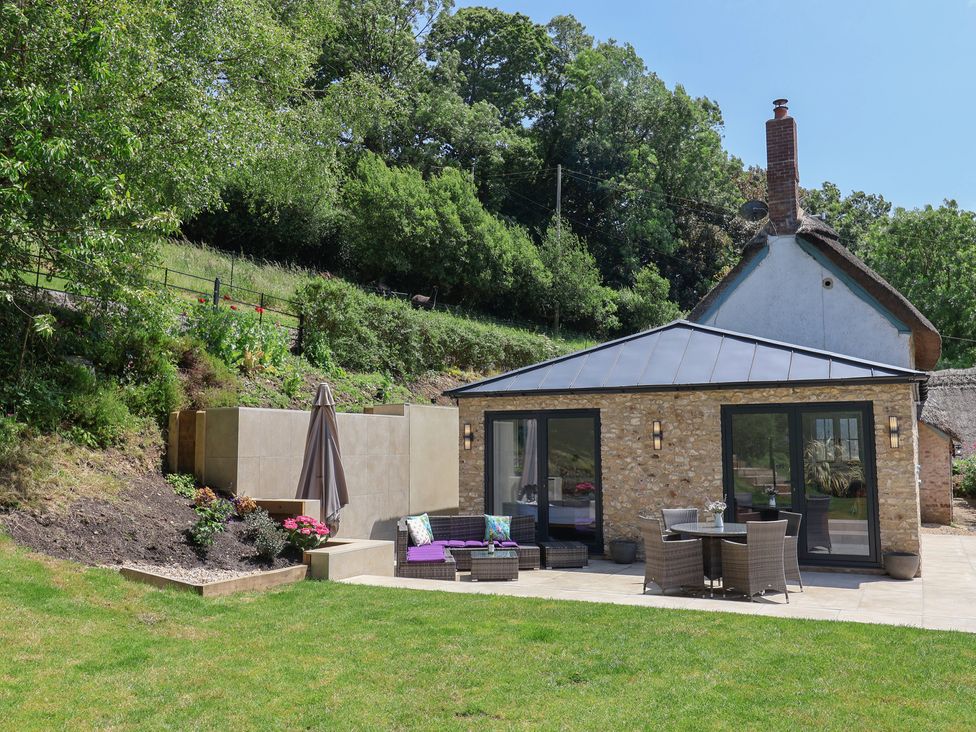 A house with a patio furniture set and a garden at Upper Cottage in Rocombe near Uplyme