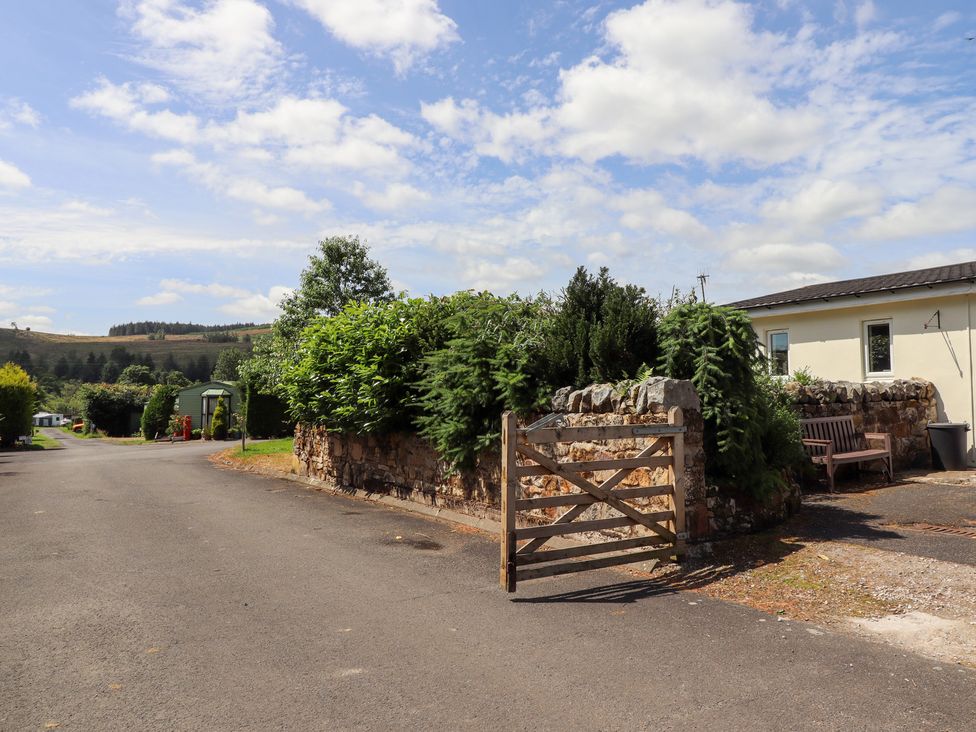 An outdoor area with a wooden gate and stone wall at Stable Cottage near Cottonshopeburnfoot