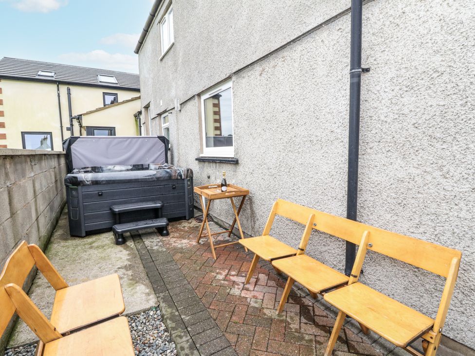 An outdoor area with a hot tub and wooden furniture at Daisy Cottage Wigton