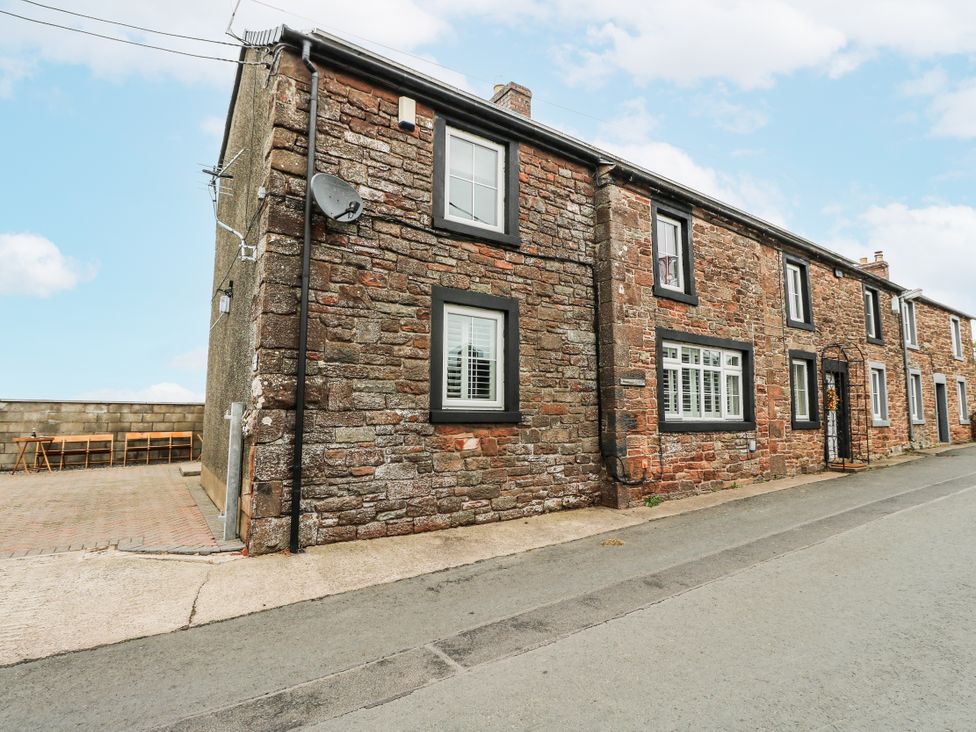 An exterior view of a stone house with windows and a door at Daisy Cottage in Wigton