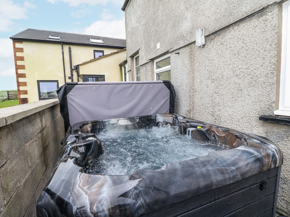 A hot tub with water next to a building at Daisy Cottage in Wigton
