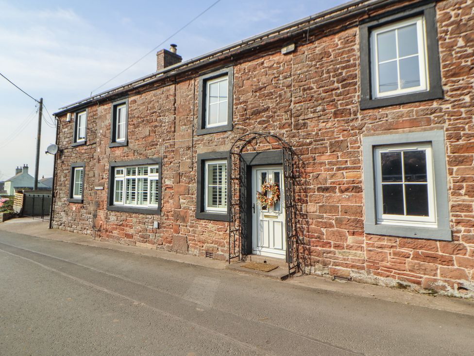 An exterior view of a stone house with a door and windows at Daisy Cottage near Wigton