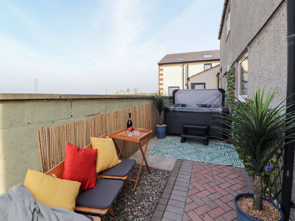 An outdoor seating area with a hot tub and plants at Daisy Cottage near Wigton