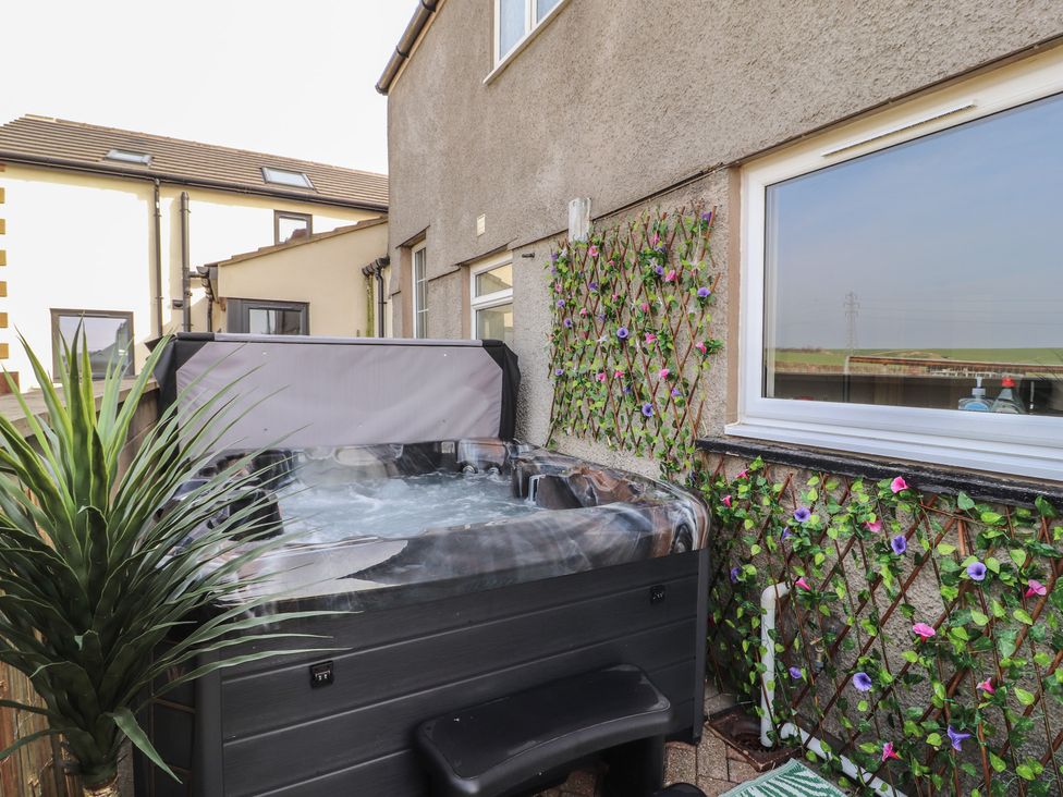An outdoor area with a hot tub next to a wall at Daisy Cottage near Wigton
