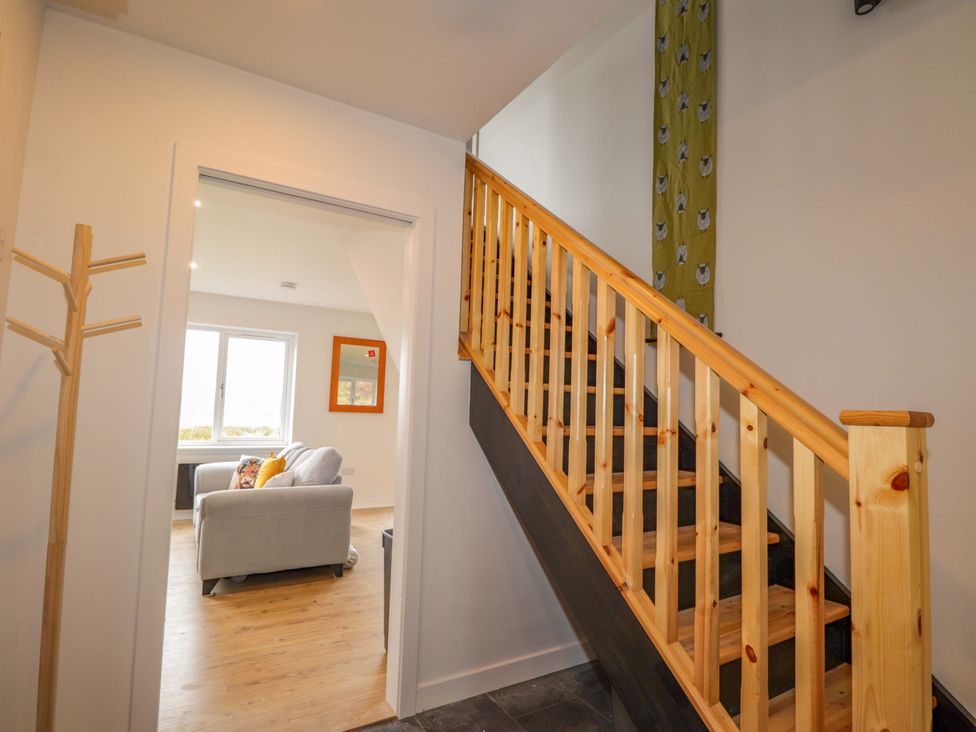 A hallway with a staircase and a coat rack at Faodail House in Portree