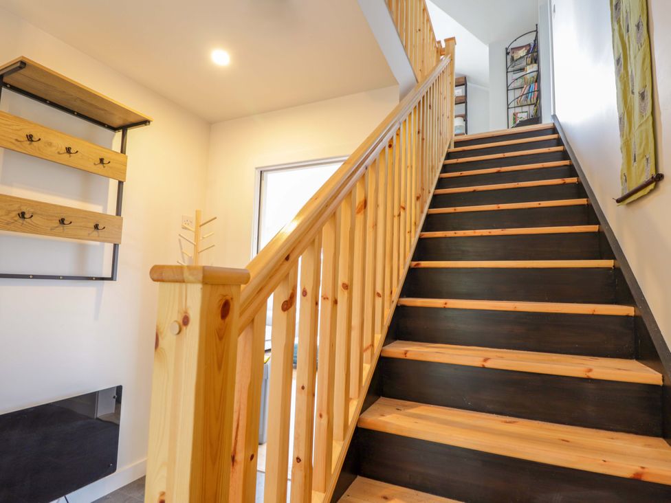 A staircase with a wooden handrail and coat rack in a hallway at Faodail House Portree