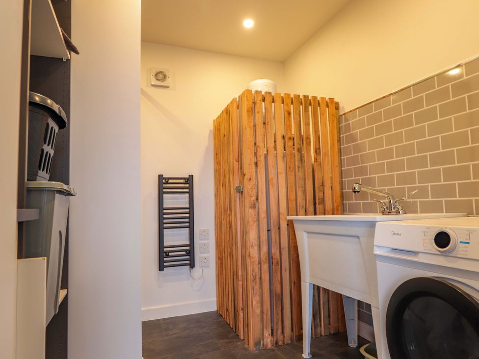 A laundry room featuring a washing machine, sink, and wooden screen at Faodail House, Portree
