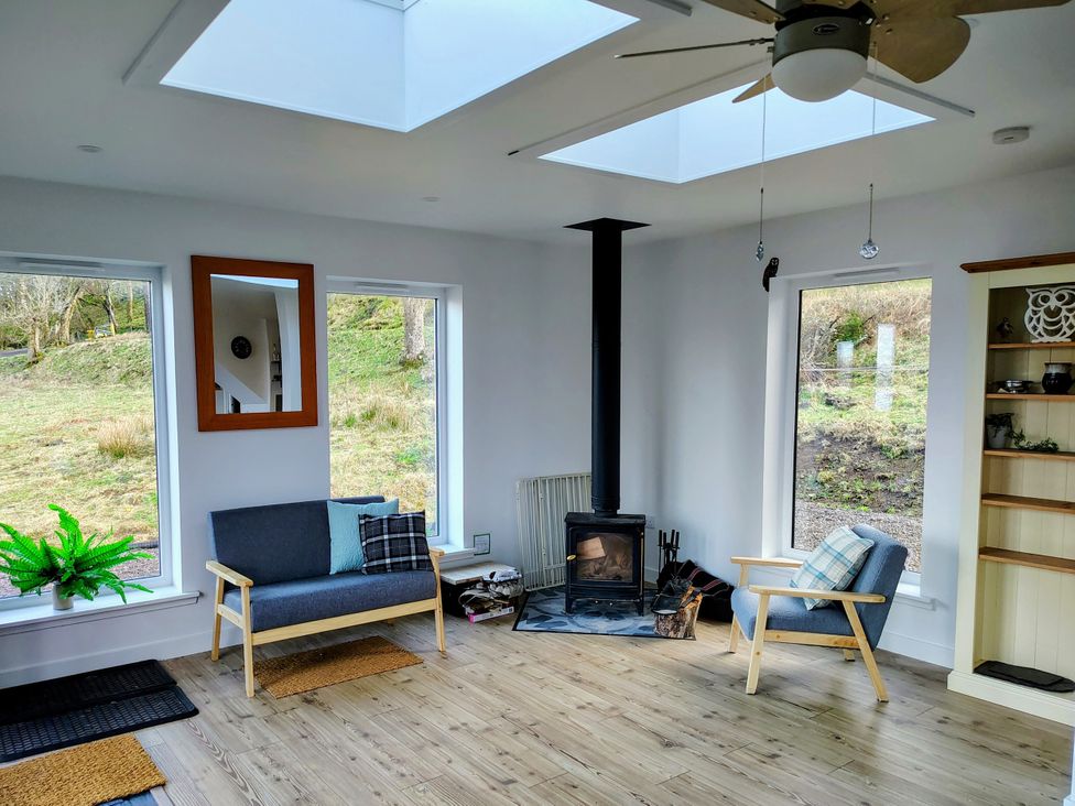 A living room with a fireplace and windows at Faodail House Kingsburgh near Uig