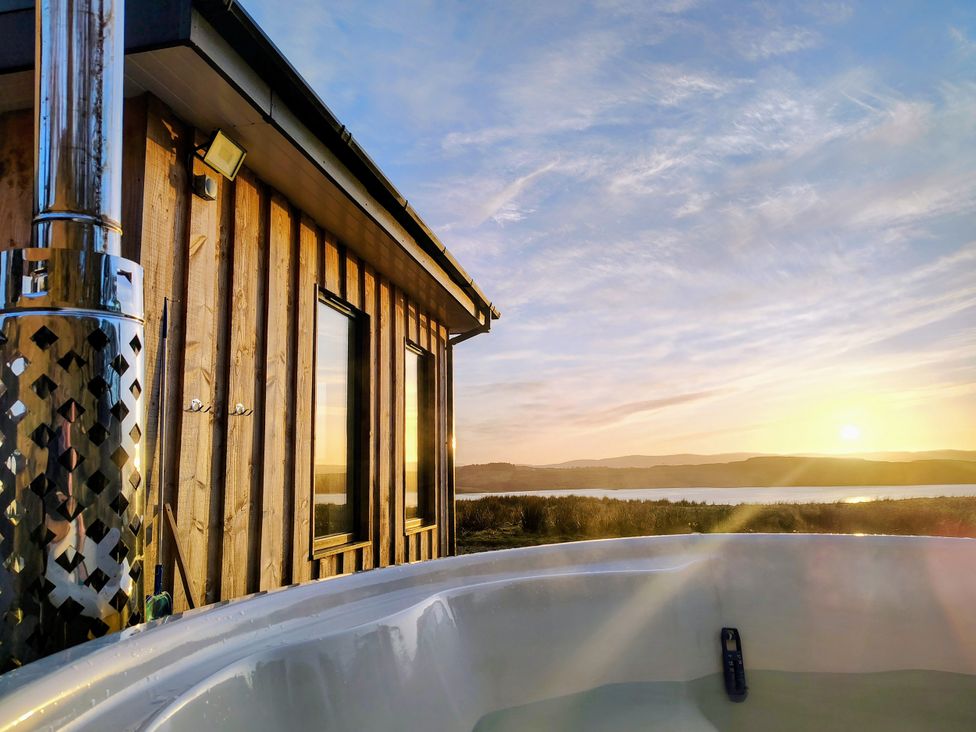 A hot tub near a wooden building at Faodail House in Kingsburgh near Uig
