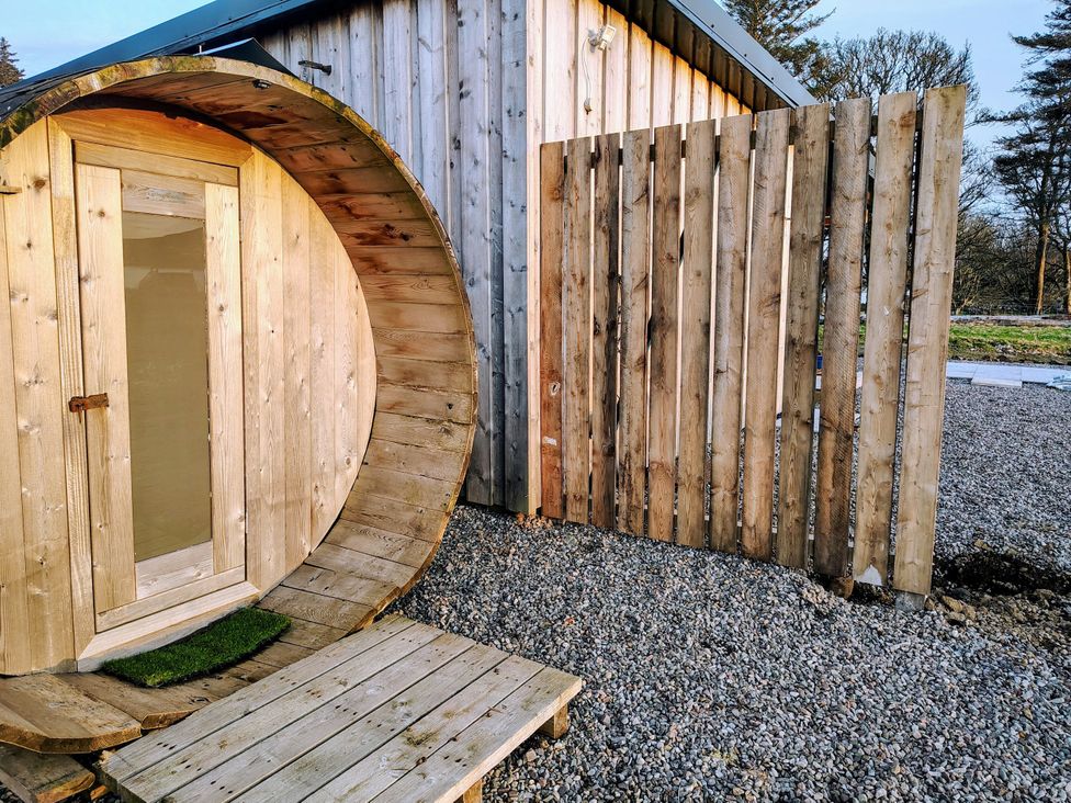 A circular wooden door and fence in an outdoor space at Faodail Studio in Kingsburgh near Uig
