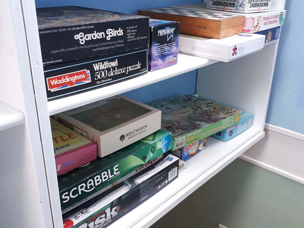 A shelf with various board games and puzzles at Taigh Phinc in Balemore near Lochmaddy, North Uist