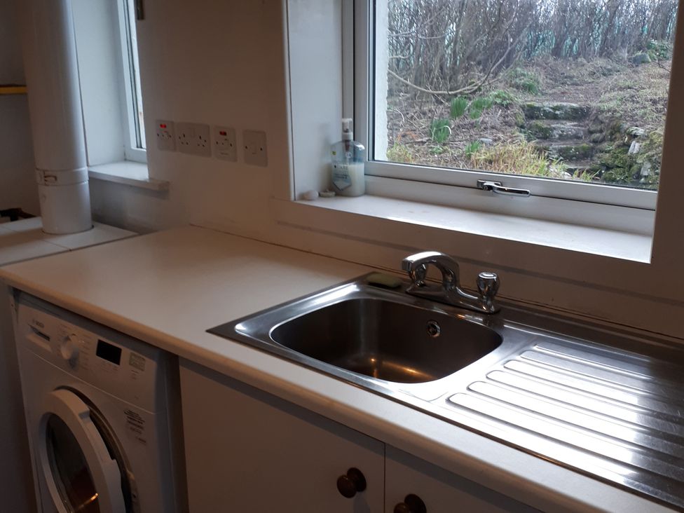 A kitchen with a sink and washing machine at Taigh Phinc near Lochmaddy, North Uist