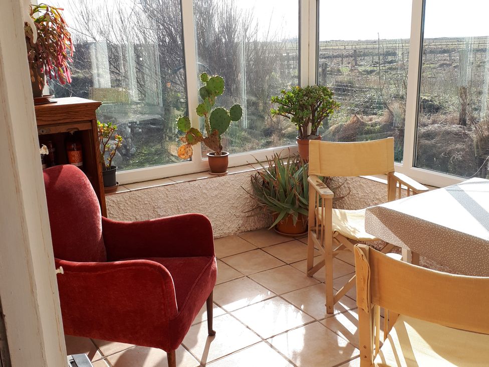 A conservatory with plants and seating at Taigh Phinc, Balemore near Lochmaddy, North Uist