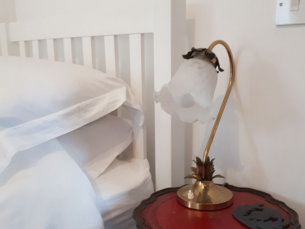 A bedside table with a lamp and pillows at Taigh Phinc in Balemore near Lochmaddy, North Uist