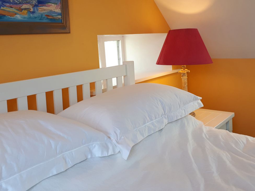 A bedroom with a white bed and red lamp at Taigh Phinc Balemore near Lochmaddy, North Uist